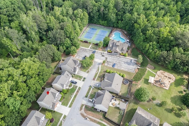aerial view of property and surrounding area featuring a pool and a forest