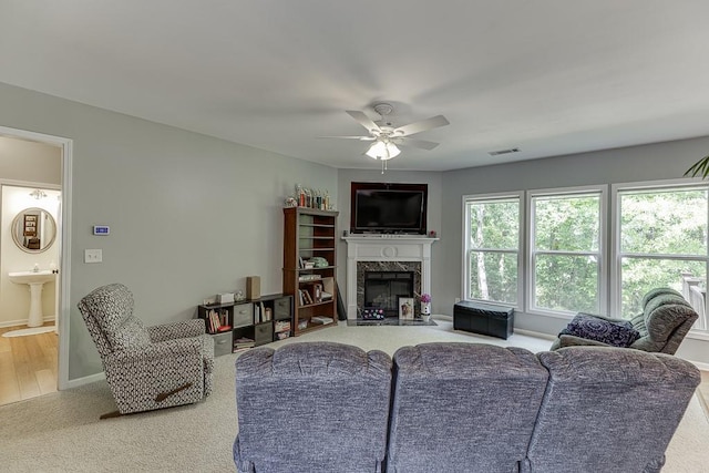 living room with ceiling fan, carpet floors, a high end fireplace, and baseboards