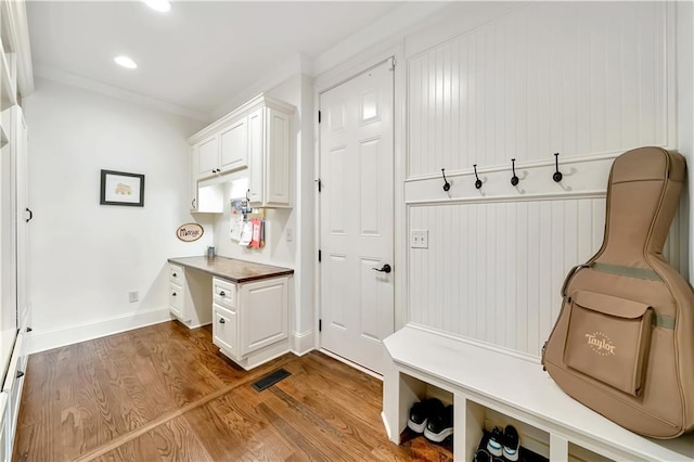 mudroom featuring recessed lighting, wood finished floors, built in desk, baseboards, and visible vents