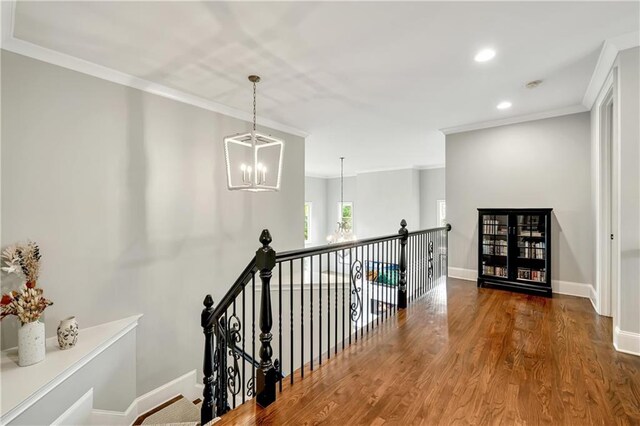 corridor with an inviting chandelier, an upstairs landing, and ornamental molding