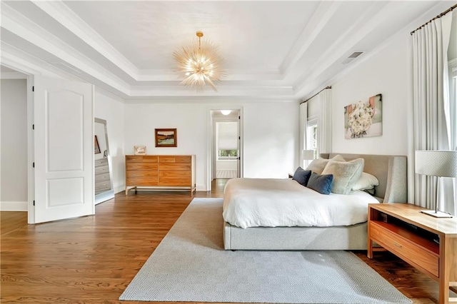bedroom featuring dark wood-style floors, an inviting chandelier, crown molding, and a tray ceiling