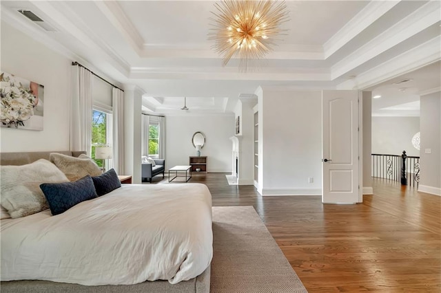 bedroom with an inviting chandelier, a tray ceiling, visible vents, ornamental molding, and wood finished floors