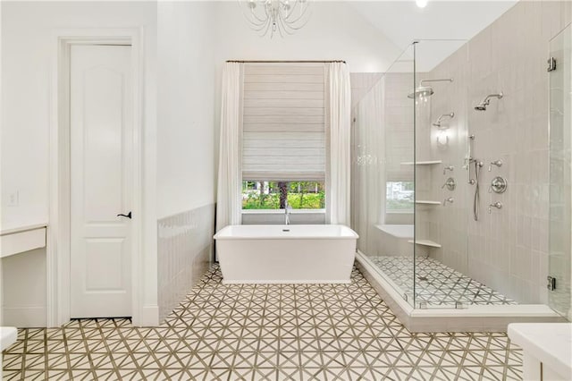 bathroom with a freestanding bath, a shower stall, vaulted ceiling, and tile patterned floors