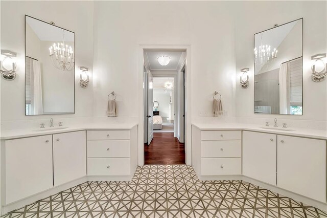 ensuite bathroom featuring tile patterned floors, two vanities, a notable chandelier, and a sink