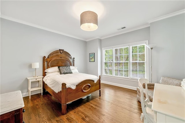 bedroom featuring crown molding, dark wood finished floors, visible vents, and baseboards