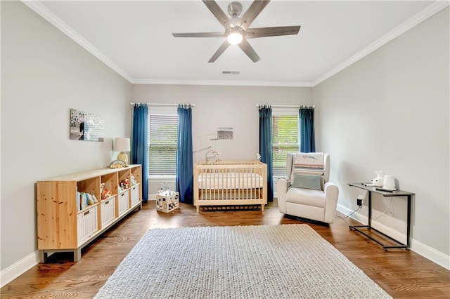 bedroom with visible vents, ceiling fan, baseboards, ornamental molding, and wood finished floors