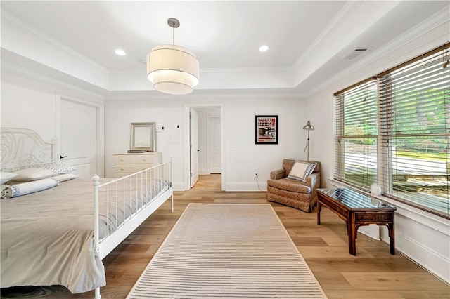 bedroom featuring light wood-style flooring, ornamental molding, and a tray ceiling