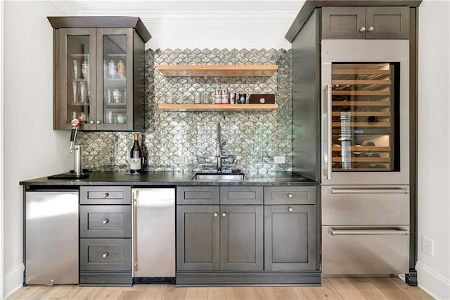 bar featuring freestanding refrigerator, backsplash, indoor wet bar, and a sink