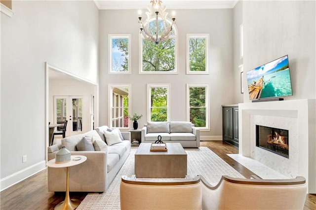 living room with french doors, wood finished floors, a fireplace with flush hearth, and a towering ceiling