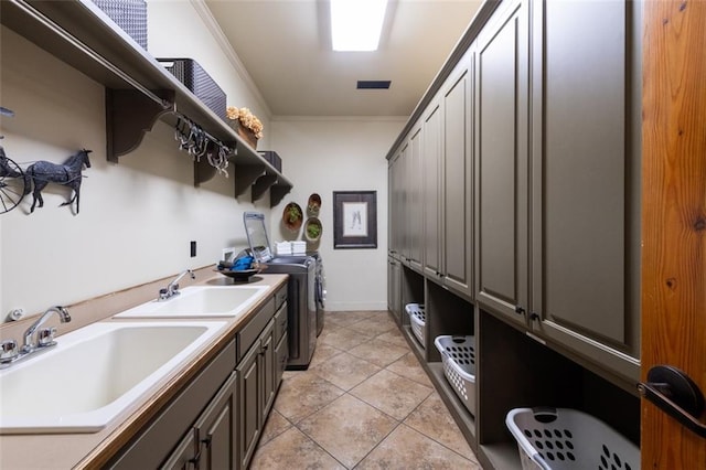 clothes washing area with washer and dryer, light tile floors, sink, and crown molding