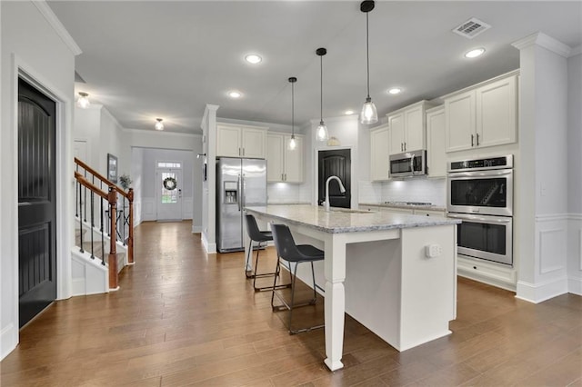 3940 Frasier Dr, Cumming, GA 30028 - kitchen featuring appliances with stainless steel finishes, ornamental molding, backsplash, dark wood-style flooring, and white cabinets