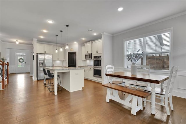 3940 Frasier Dr, Cumming, GA 30028 - kitchen featuring stainless steel appliances, crown molding, a decorative wall, white cabinets, and a center island with sink