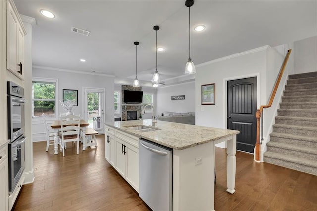 3940 Frasier Dr, Cumming, GA 30028 - kitchen featuring stainless steel appliances, a stone fireplace, crown molding, dark wood finished floors, and white cabinets