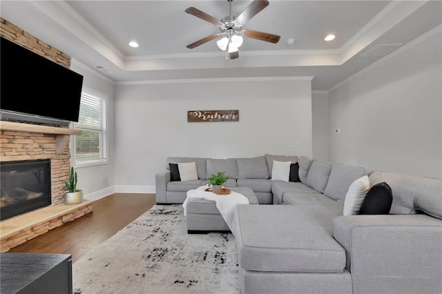 3940 Frasier Dr, Cumming, GA 30028 - living area featuring wood finished floors, a tray ceiling, a ceiling fan, crown molding, and a stone fireplace