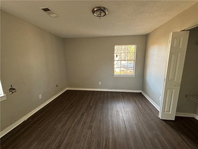 spare room featuring dark hardwood / wood-style flooring and a textured ceiling