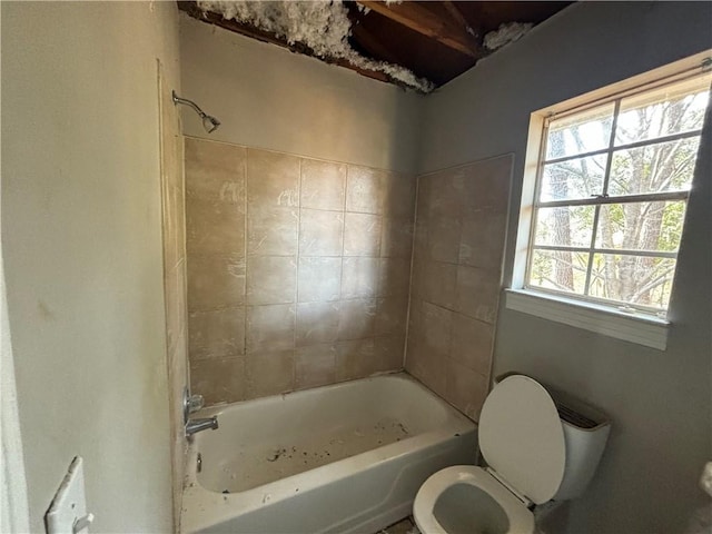 bathroom featuring tiled shower / bath combo and toilet