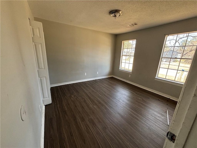 spare room featuring dark wood-type flooring and a textured ceiling