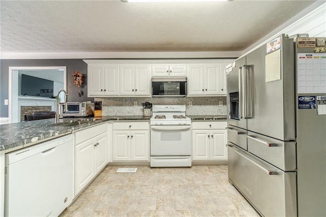 1623 Pratt Rd, Covington, GA 30014 - kitchen featuring appliances with stainless steel finishes, a textured ceiling, white cabinets, and dark stone countertops