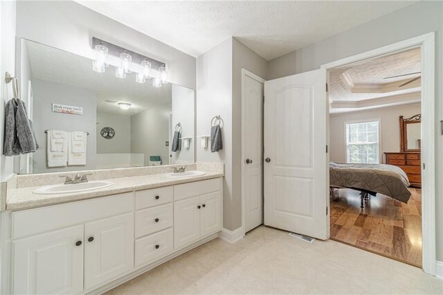 1623 Pratt Rd, Covington, GA 30014 - full bath featuring double vanity, ensuite bathroom, a textured ceiling, and a tray ceiling