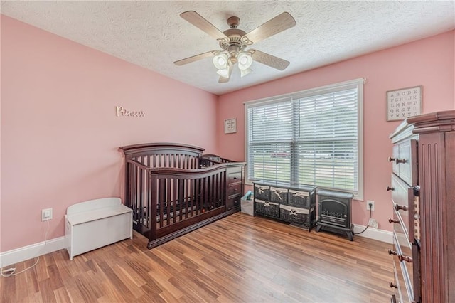 1623 Pratt Rd, Covington, GA 30014 - bedroom featuring wood finished floors, ceiling fan, a textured ceiling, and a crib