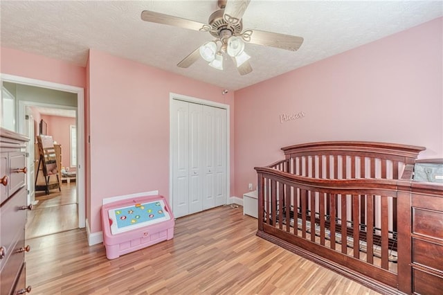 1623 Pratt Rd, Covington, GA 30014 - bedroom featuring wood finished floors, a closet, a textured ceiling, ceiling fan, and a crib