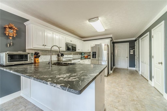 1623 Pratt Rd, Covington, GA 30014 - kitchen with appliances with stainless steel finishes, a peninsula, tasteful backsplash, white cabinets, and a textured ceiling