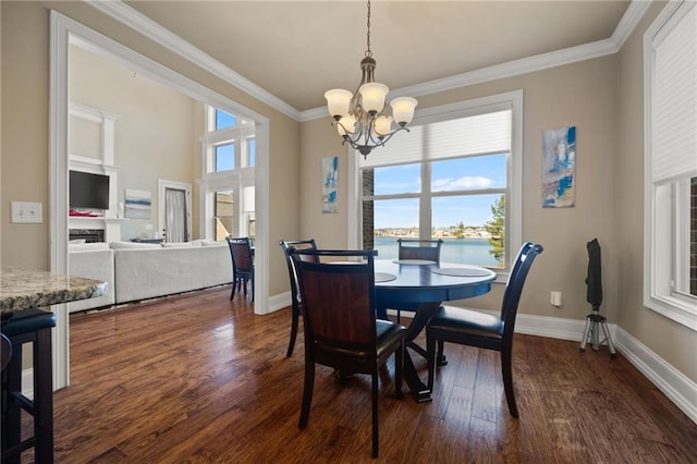 dining area with dark hardwood / wood-style flooring, ornamental molding, a chandelier, and a water view