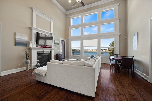 living room featuring crown molding, ceiling fan, dark hardwood / wood-style floors, and a high ceiling