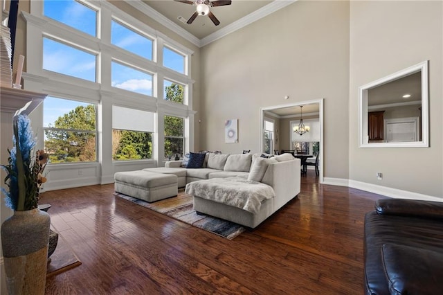 living room featuring a high ceiling, crown molding, dark wood-type flooring, and ceiling fan with notable chandelier