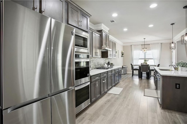 kitchen featuring visible vents, decorative backsplash, appliances with stainless steel finishes, ornamental molding, and a sink