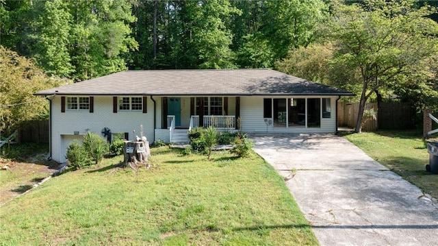 view of front of property with covered porch, fence, a front yard, brick siding, and driveway