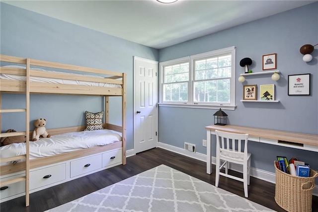 bedroom with baseboards, visible vents, and wood finished floors