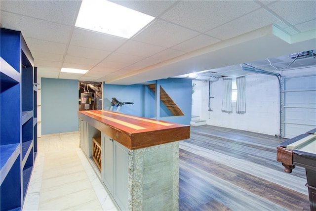 interior space with water heater, light wood-style floors, and a drop ceiling
