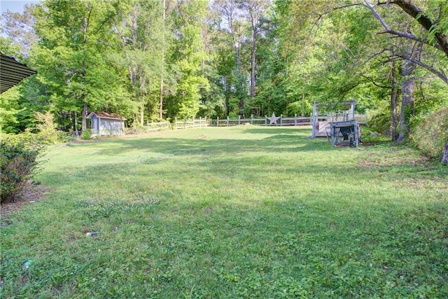view of yard with an outdoor structure, a forest view, and fence
