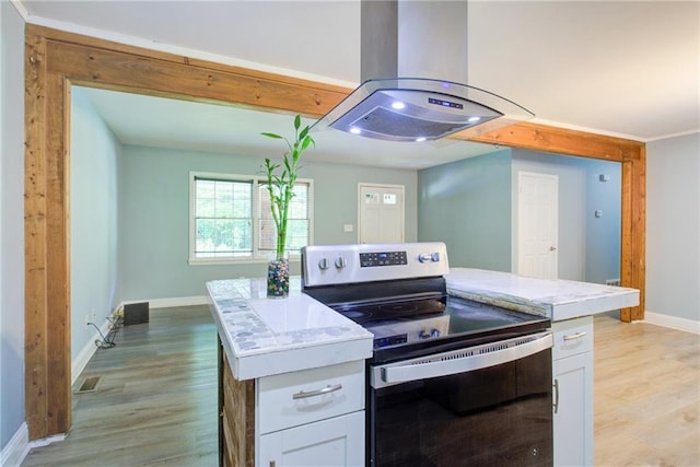 kitchen featuring light wood-style floors, island range hood, baseboards, and stainless steel electric range