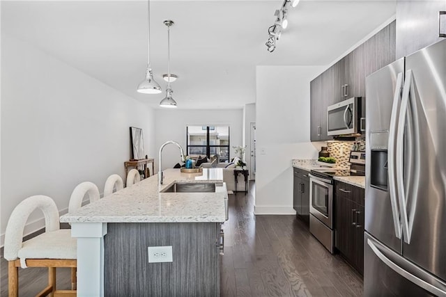 kitchen with pendant lighting, sink, dark hardwood / wood-style floors, an island with sink, and appliances with stainless steel finishes