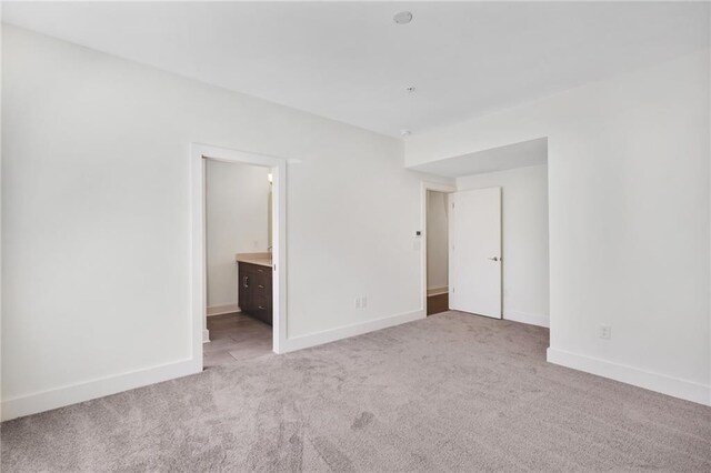 interior space featuring ensuite bathroom and light colored carpet