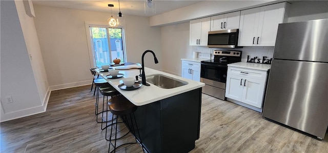 kitchen with a center island with sink, sink, white cabinets, and stainless steel appliances