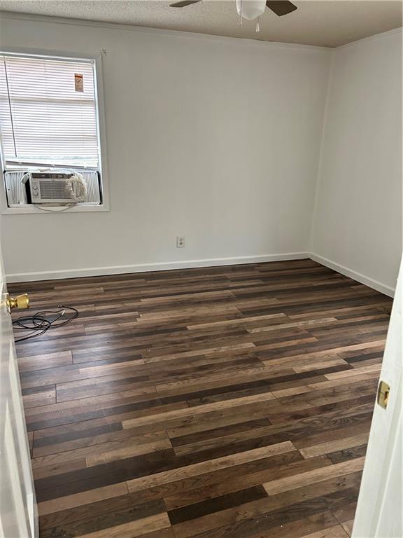 spare room with a textured ceiling, cooling unit, dark wood-type flooring, and ceiling fan