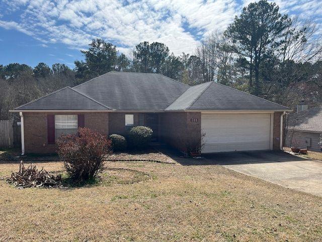 ranch-style home featuring driveway, an attached garage, and a front yard