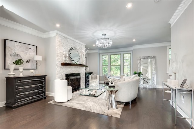 living room featuring dark wood-type flooring, ornamental molding, a stone fireplace, and an inviting chandelier