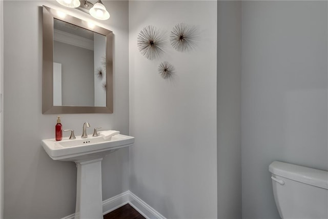 bathroom featuring ornamental molding, toilet, and sink