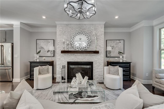 living room with crown molding, a chandelier, hardwood / wood-style floors, and a fireplace