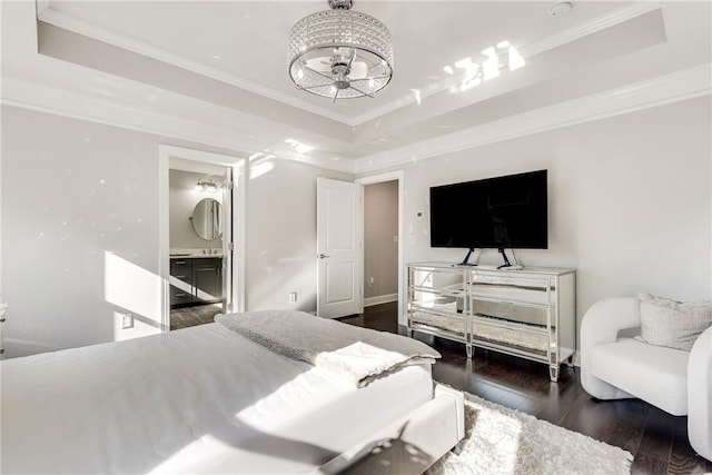 bedroom featuring crown molding, dark wood-type flooring, a raised ceiling, and ensuite bathroom