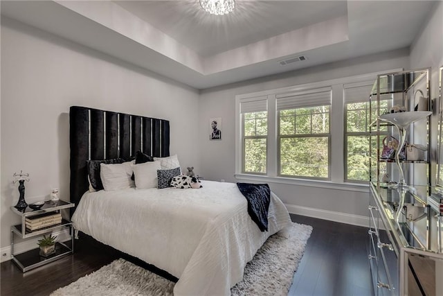 bedroom with a tray ceiling and dark hardwood / wood-style flooring