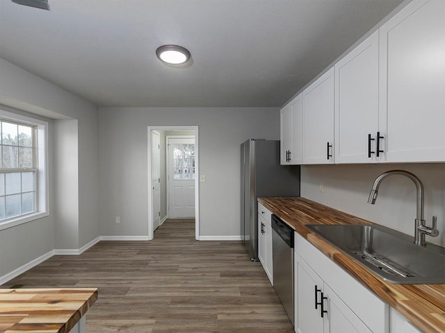 kitchen featuring wood counters, sink, white cabinetry, and dishwasher