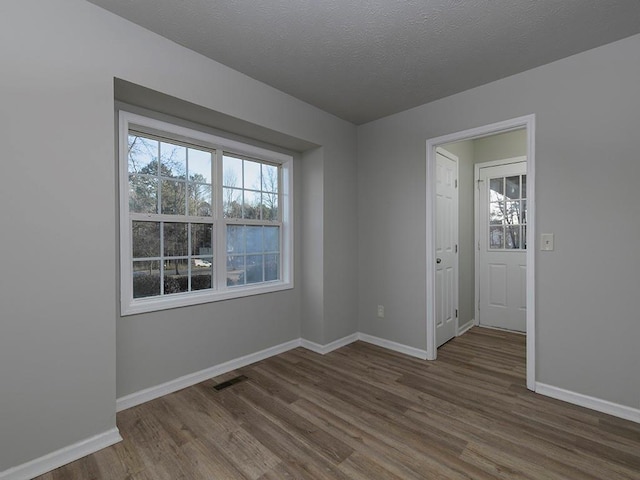 spare room featuring wood-type flooring and a textured ceiling