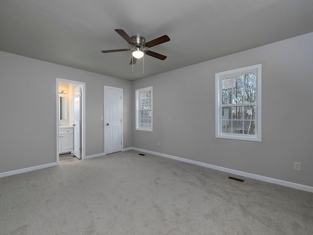 unfurnished bedroom featuring light carpet, ensuite bath, and ceiling fan