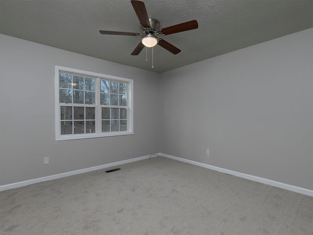 spare room featuring ceiling fan, light colored carpet, and a textured ceiling