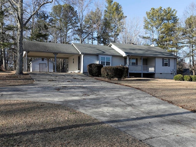 view of front of home with a carport, a storage unit, and a porch